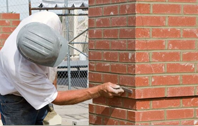 Craftsperson repairing mortar joints on a brick building